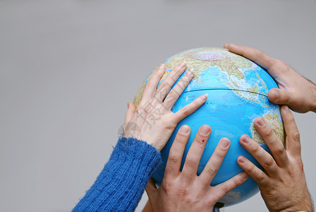 地球蓝色手放在地球的模型上背景
