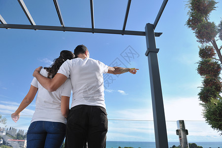 幸福的轻情侣户外阳台上享受浪漫的放松,背景海洋蓝天背景图片