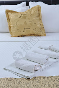 豪华酒店客房床上的白色毛巾,背景为黄色枕头图片
