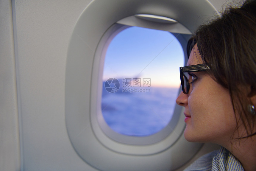 快乐的轻旅游妇女坐飞机上看着温多夫,度假图片