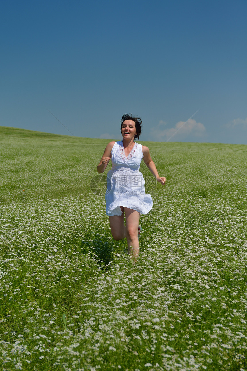 轻快乐的女人绿色的田野,蓝天的背景图片