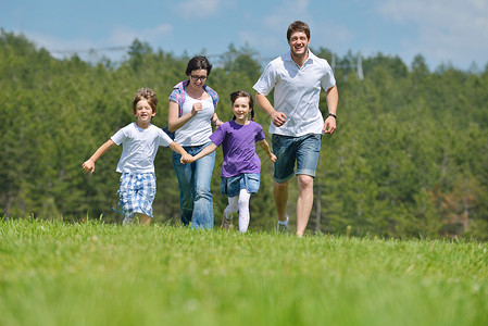 快乐的轻家庭他们的孩子玩得开心,大自然中放松,背景蓝天微笑高清图片素材