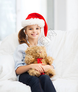 诞节,冬天,幸福的微笑的女孩戴着诞老人的帽子,家里泰迪熊图片