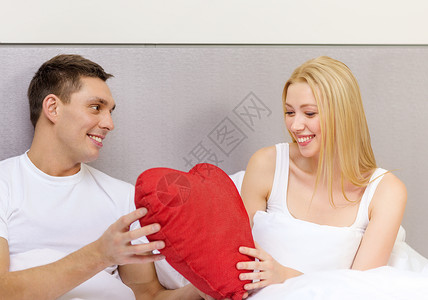 酒店,旅行,关系,假期幸福的微笑的夫妇床上与红色心形枕头图片