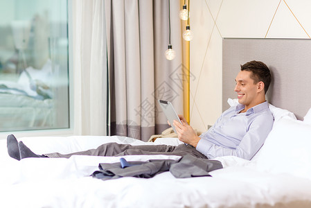 商业,技术,互联网酒店快乐的商人与平板电脑电脑躺酒店床上图片