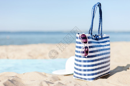 帽子夏天的白色草帽,太阳镜袋子躺沙滩上的沙子里图片