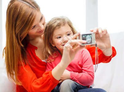 养育子女照片家庭,孩子,技术快乐的人的微笑的母亲女儿与数码相机背景