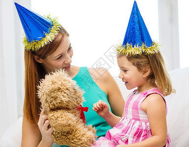 家庭,孩子,庆祝快乐的人的快乐的母亲女儿戴着蓝色的派帽泰迪熊图片