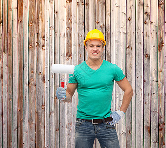 维修施工维护理念带油漆滚筒的防护头盔中微笑的男手工工人图片