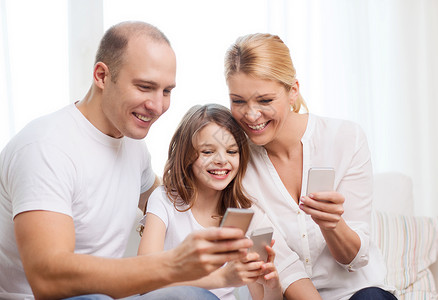 家庭,孩子,技术家庭微笑的父母小女孩家里智能手机图片