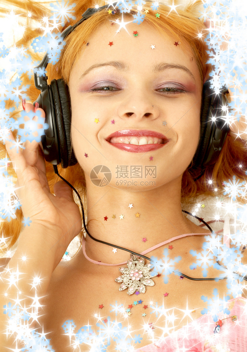 圣诞照片,微笑的红头发女孩在听音乐图片