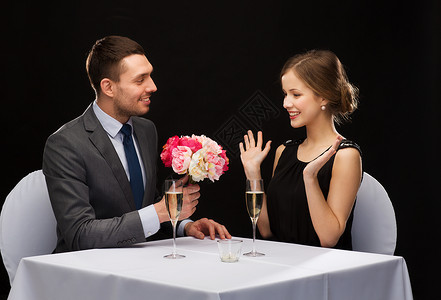 微笑的男人在餐厅给女人送花图片