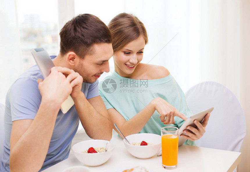 食物,家庭,夫妇技术微笑夫妇与平板电脑阅读新闻家里吃早餐图片