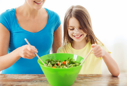 微笑的小女孩母亲混合沙拉厨房背景图片