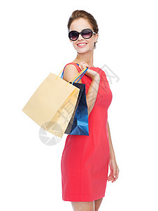 购物,销售,礼物假日微笑的女人穿着红色连衣裙太阳镜带购物袋漂亮的高清图片素材