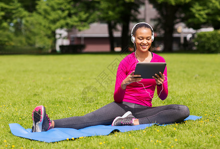 健身,公园,技术运动微笑的非裔美国妇女与平板电脑耳机垫子户外图片