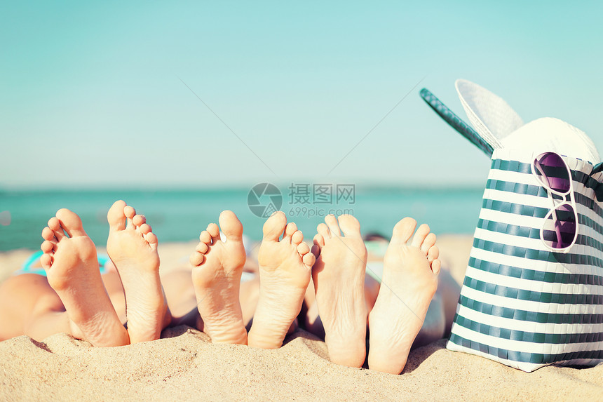 暑假,日光浴修脚的三个女人躺海滩上,戴着草帽,太阳镜袋子图片