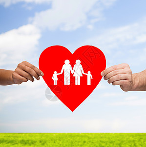 健康,爱,收养关系的特写多种族夫妇的手大红心与家人孩子蓝天上的草背景背景图片
