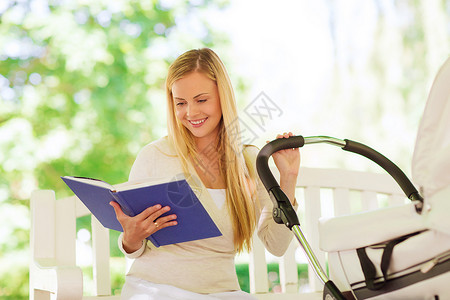 家庭,孩子,休闲,教育父母的快乐的母亲与婴儿车阅读书籍公园图片