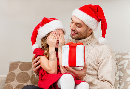 来自女儿礼物家庭,诞节,幸福人的微笑的女儿闭着眼睛等待来自法特的礼物背景