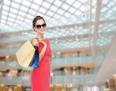 购物,销售,诞节假日微笑优雅的女人穿着红色连衣裙太阳镜带购物袋可爱的高清图片素材