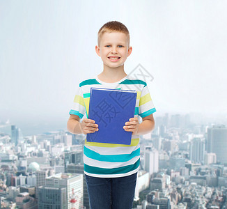 教育,学校的微笑的小男孩与蓝色的书与城市背景图片
