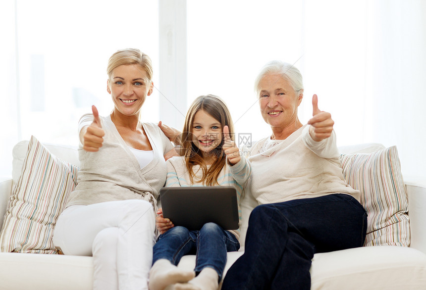 家庭,代,技术人的微笑的母亲,女儿祖母与平板电脑电脑坐家里的沙发上图片