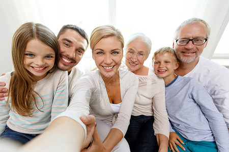 家庭,幸福,世代人的幸福的家庭坐沙发上,用相机智能手机家里自画像图片