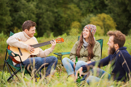 冒险,旅行,旅游人的群微笑的朋友吉他坐椅子上露营图片