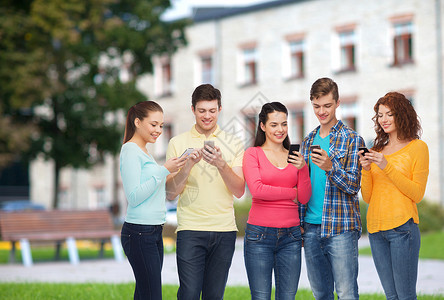 友谊,技术,教育,学校人的群微笑的青少校园背景下用智能手机图片