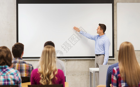 教育高中队合作人的微笑的老师站学生前,教室的白板上展示些东西图片