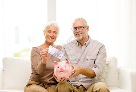 家庭,储蓄,龄人的微笑的老夫妇与钱储蓄罐家里图片
