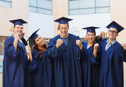 教育,毕业人的群微笑的学生穿着沙黑板长袍户外胜利的手势图片