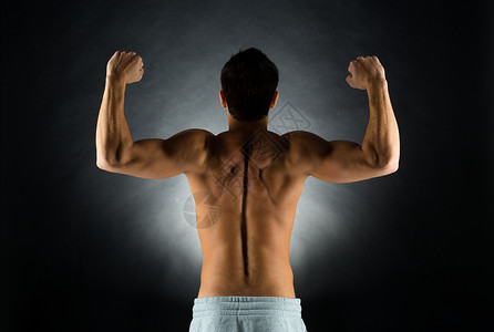 运动,健美,力量人的轻人站黑色背景上,背部弯曲的肌肉图片