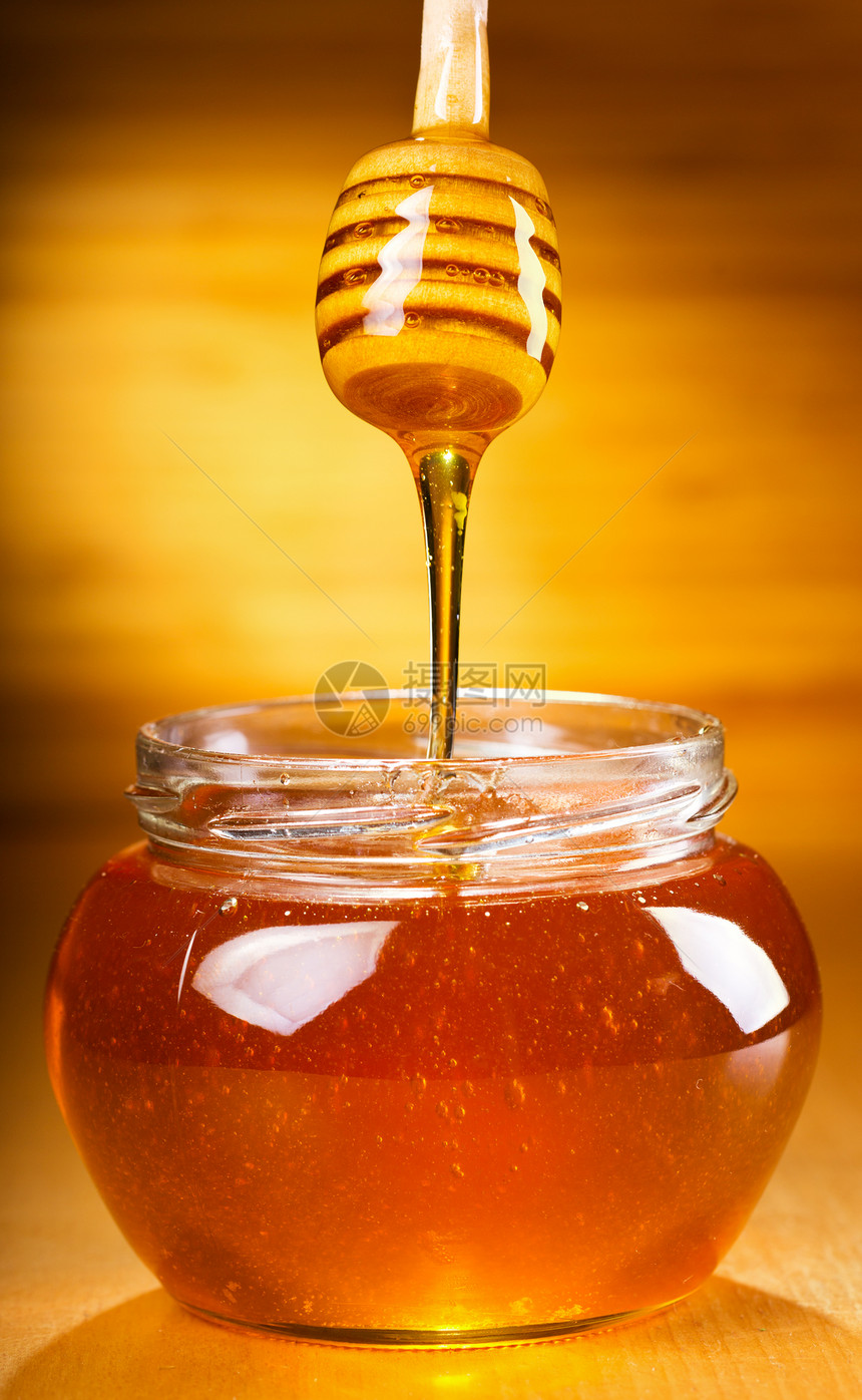 蜂蜜倒进木桌上的碗里图片