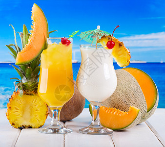 热带鸡尾酒与新鲜水果海滩上背景图片