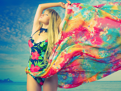 幻想风海滩上穿着彩色连衣裙的豪华金发女郎背景