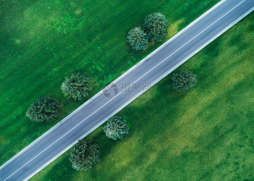 春天的傍晚,美丽的绿色田野俯瞰道路美丽的风景与空旷的乡村道路,树木,绿草穿过公园的高速公路飞行无人机的顶部视图图片