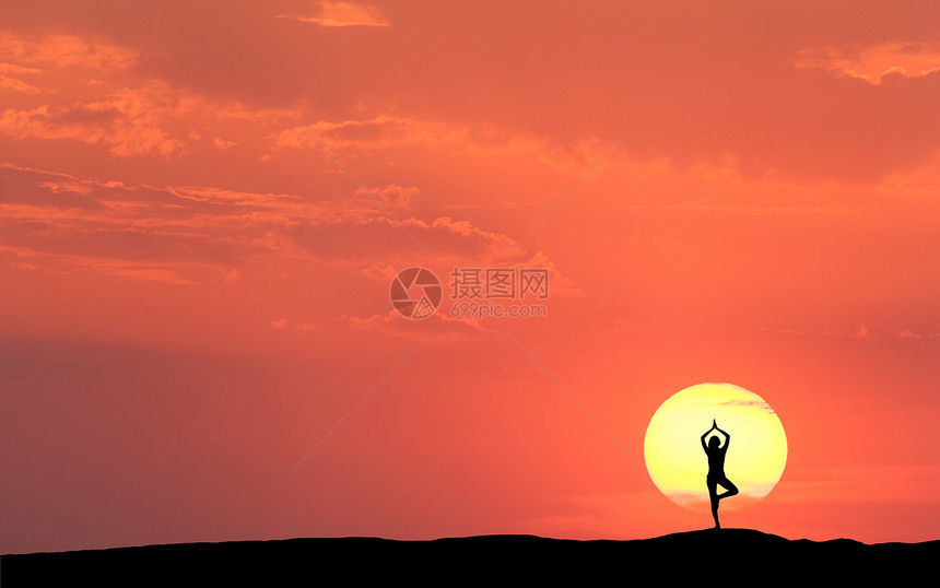 个站立的运动妇女的轮廓,练瑜伽,举手臂山上的太阳彩色橙色天空与云的背景日落时与冥想的女孩景观健身图片