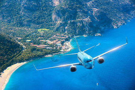 飞机夏天日出时飞越岛屿海洋风景白色客机,海滨,山脉,天空碧水蓝色客机旅行度假旅游业蓝色飞机太阳升背景