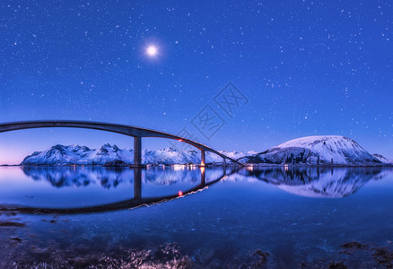 桥紫色的星空,美丽的倒影水中夜风景桥,雪山,天空满月明亮的星星反射海里挪威洛福滕岛的冬天桥紫色的星背景图片