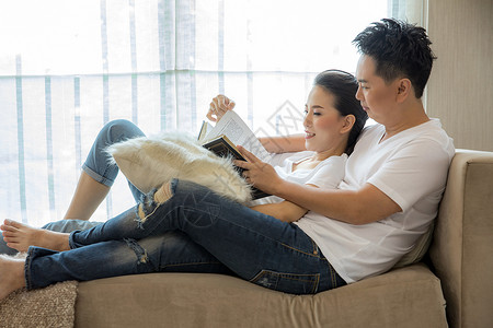 轻夫妇当代房子的客厅里阅读书籍,了解生活方式的图片