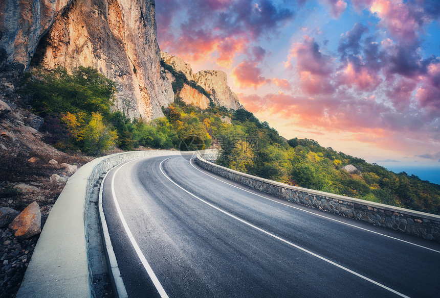 日落时的山路美丽的天空五颜六色的景观,高岩石,蜿蜒的沥青路,树木蓝天与红色橙色的云秋天旅行山中高速公路的风图片