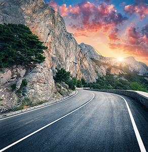 日落时的山路美丽的天空五颜六色的景观,高岩石,蜿蜒的沥青路,树木蓝天与红色橙色的云夏天旅行山中巷道的风景背景图片