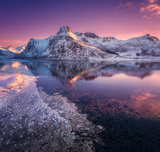 雪山的鸟瞰,蓝色的大海霜冻的海岸,挪威洛福滕岛五颜六色的日落时,水紫色的天空中反射冬天的风景雪覆盖的岩石,峡湾冰背景图片