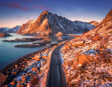 鸟瞰美丽的山路附近的海洋,山脉,紫色的天空日落洛福滕岛,挪威冬天顶部的道路,汽车,高雪岩与石头,海岸线,蓝色的水岩石高清图片素材