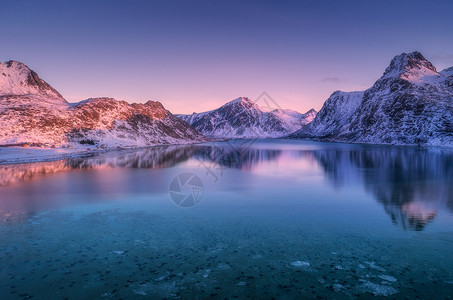 比利茨基黄昏时,雪覆盖的山脉五颜六色的天空反射水中冬天的景观大海,雪岩,紫色的天空,日落时的倒影洛芬岛,挪威黄昏自然背景