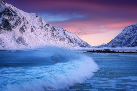 挪威洛福腾群岛的沙滩上,冬天蓝色的大海波浪风景雪山,五彩缤纷的天空粉红色紫色的云,绿松石的水挪威海滨背景图片