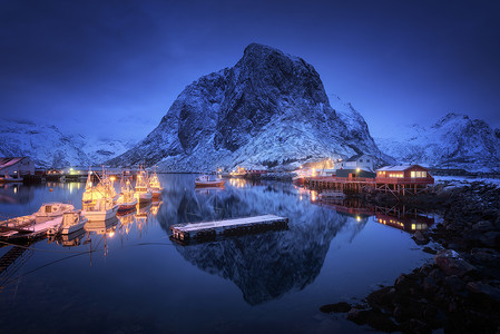 晚上船的渔村,洛芬岛,挪威冬天的风景房子,码头,照明,雪山,大海,蓝色多云的天空黄昏时反射水中挪威罗布尔海岸高清图片素材