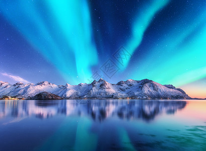 吸磁北极光雪覆盖了挪威洛芬岛的山脉北极光星空,极地的灯光雪石反射水中夜间冬季景观与极光,海洋旅行北极光雪背景